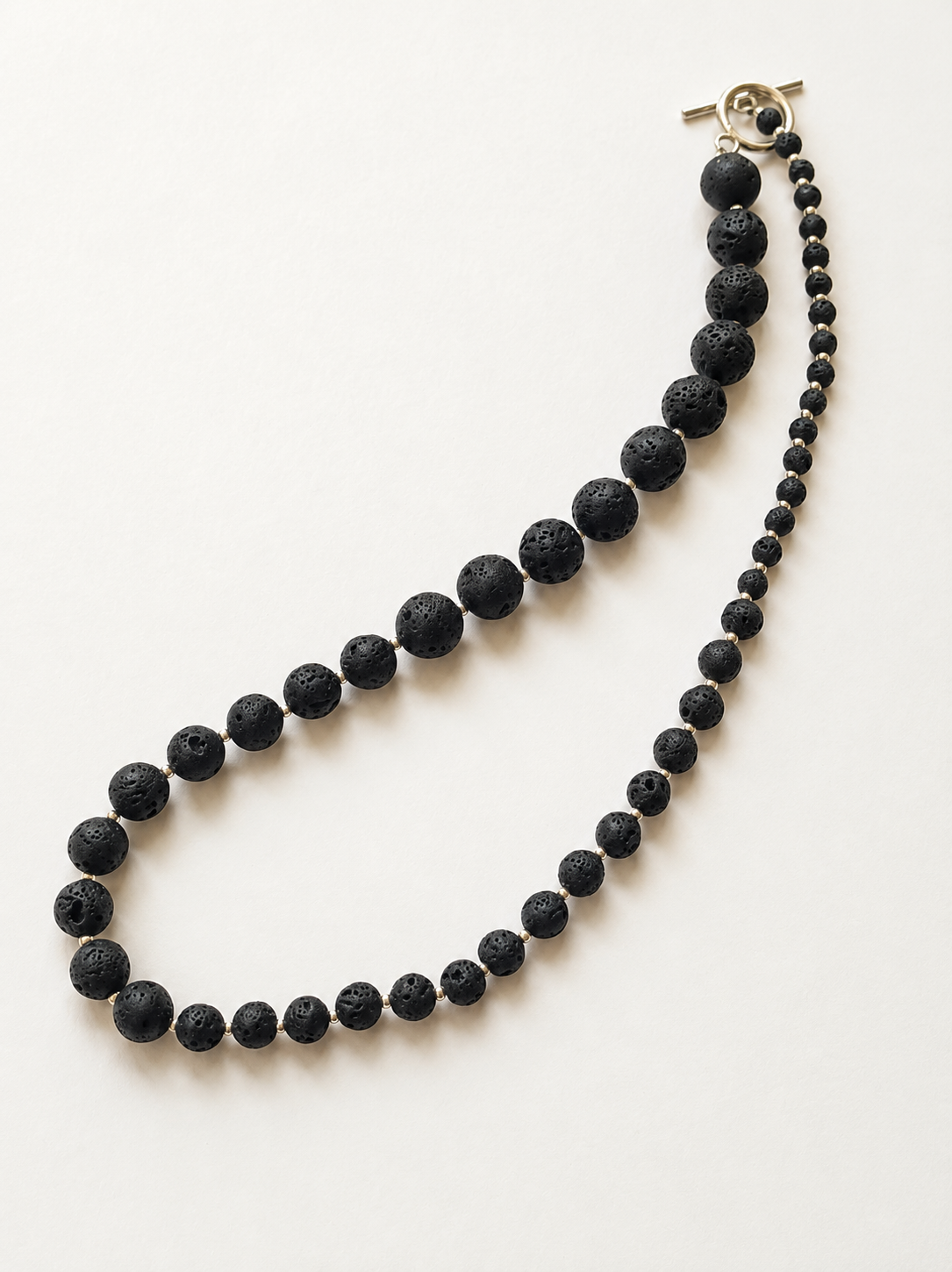 Detailed view of graduated black lava beads with silver Japanese Miyuki accents
