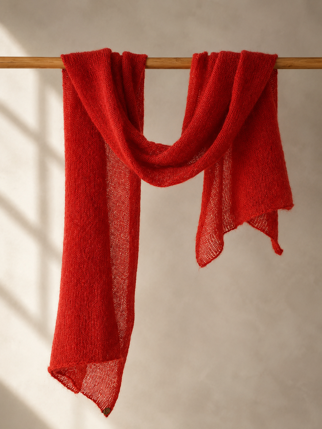 Crimson Flame silk mohair shawl draped over a wooden rail in elegant soft folds