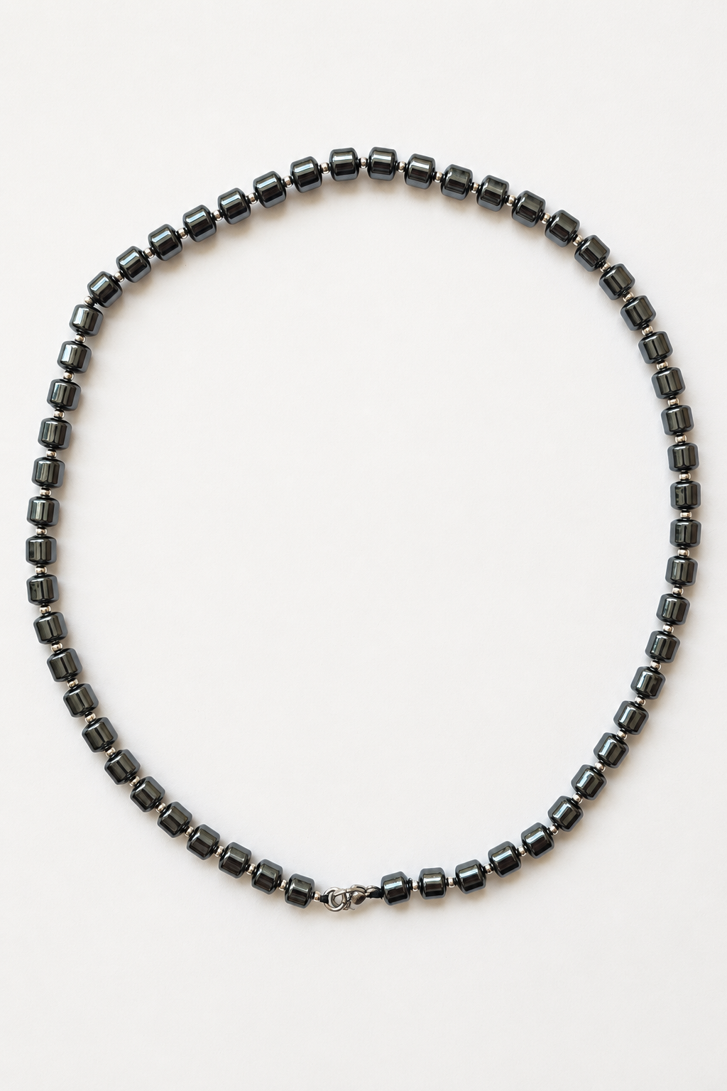 ematite column necklace with silver accents arranged on a light neutral background