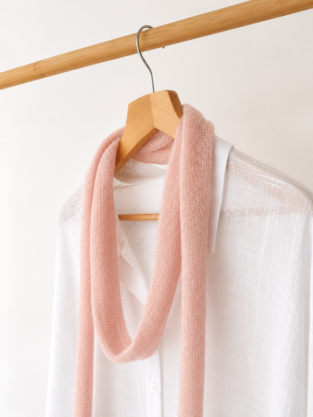 Lightweight blush skinny scarf styled on wooden hanger