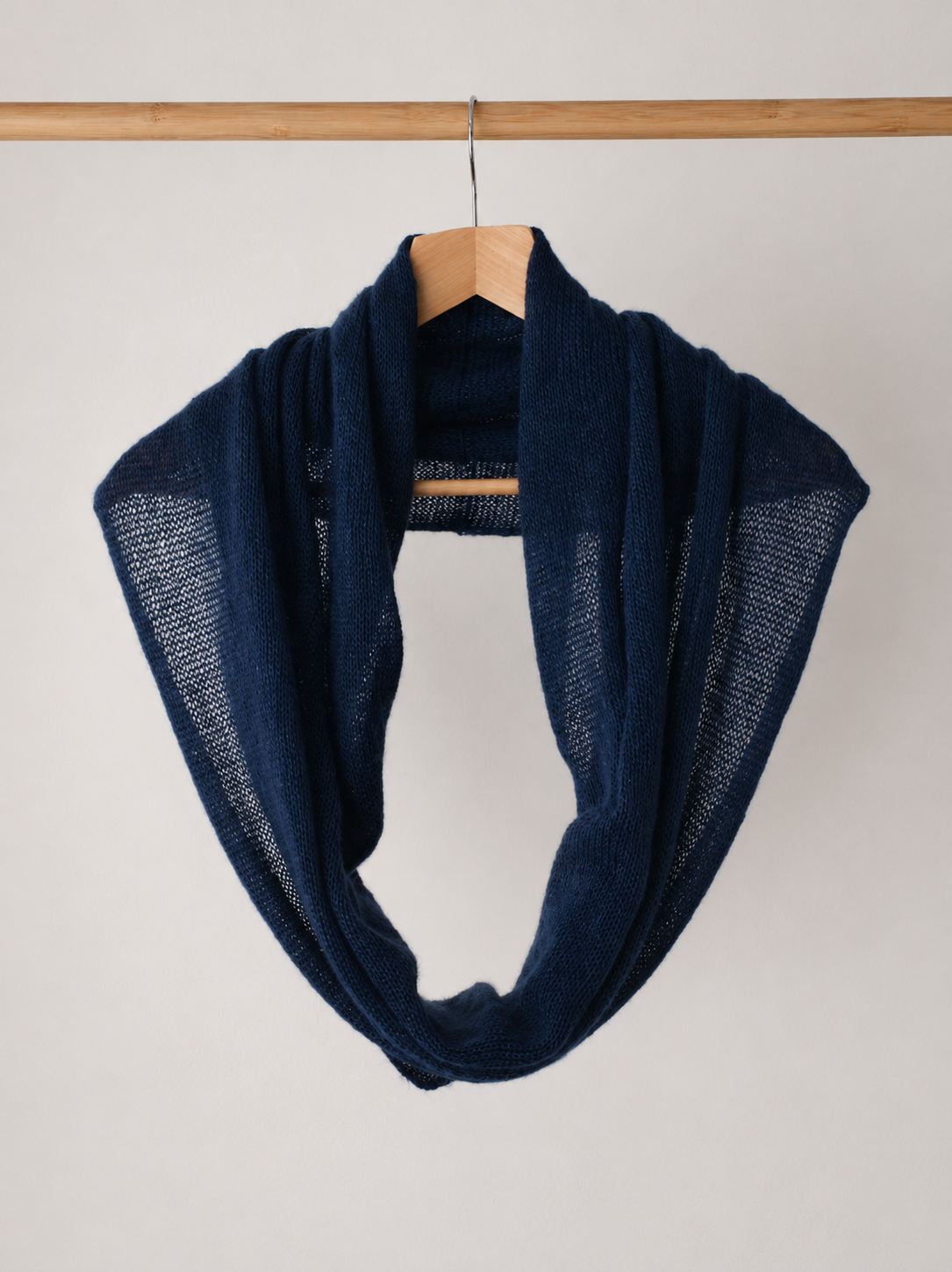 Midnight navy silk mohair infinity scarf hanging on a wooden hanger.
