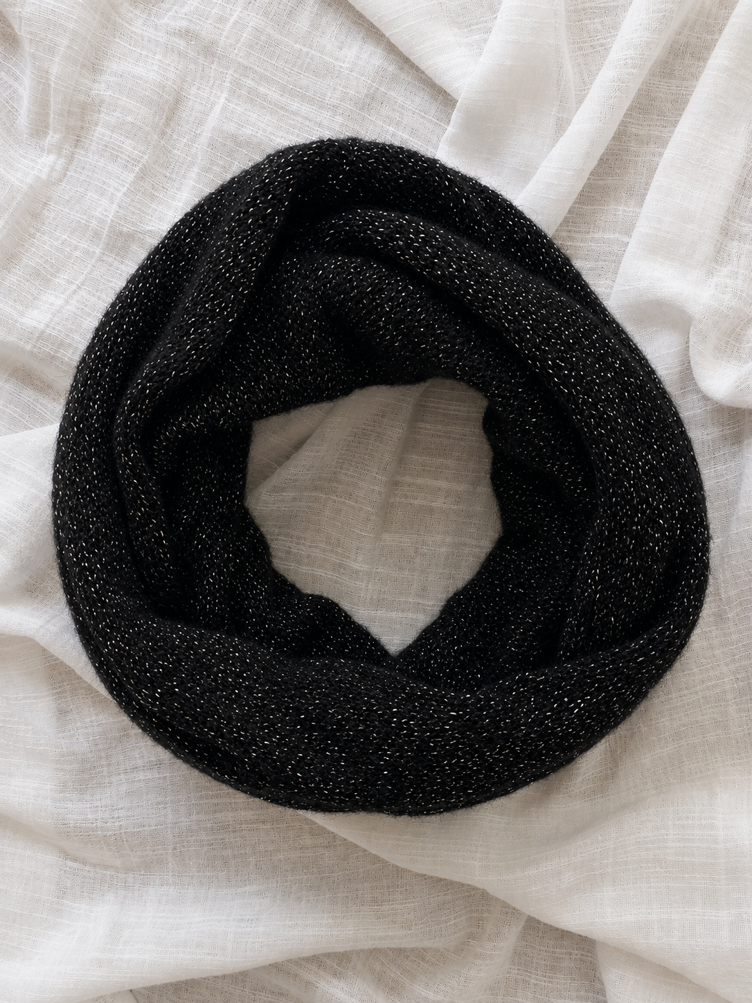 Rolled black mohair infinity scarf highlighting its soft knit and subtle shimmer