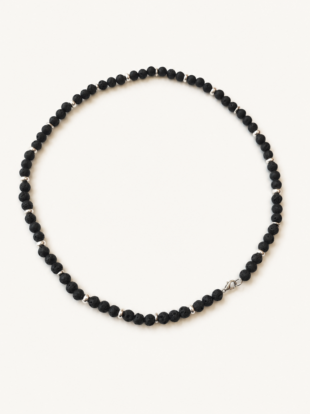 Angled full view of a black lava bead necklace with evenly spaced silver-coloured details